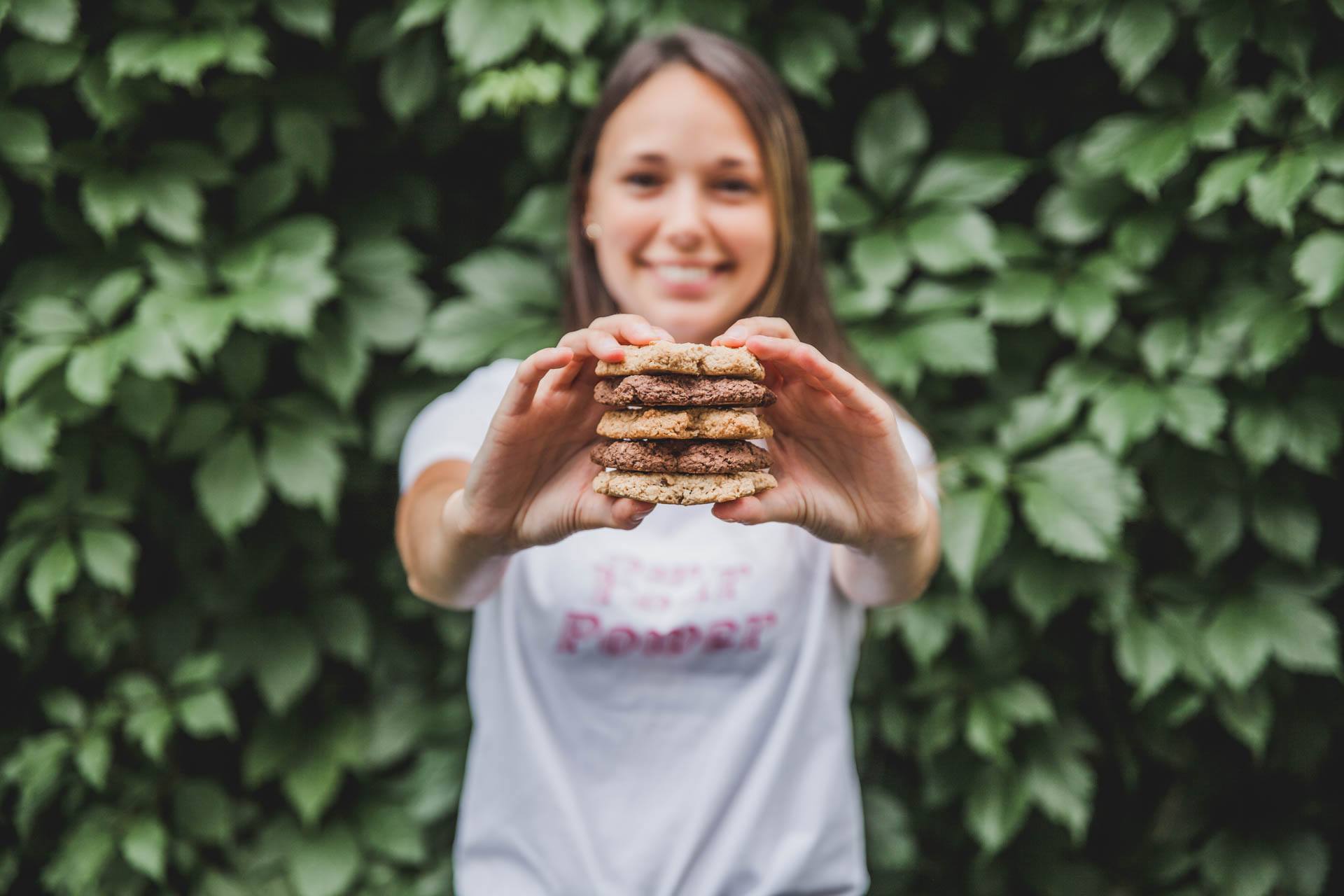 Femme qui sourit et qui tient cinq galette à l'avoine Vitali-T empilées dans les mains