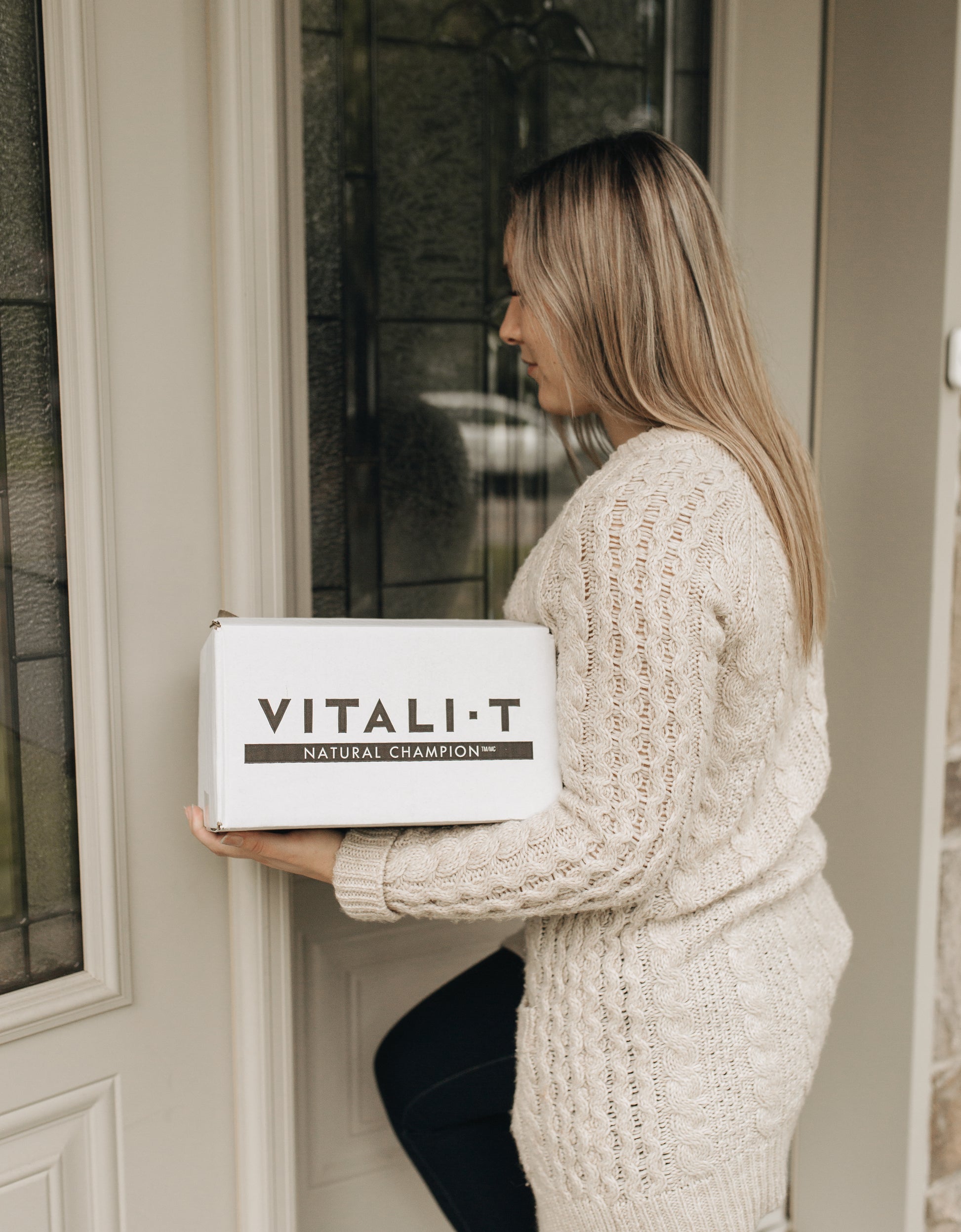 Femme tenant boîte de 24x85G de collation à l'avoine multiple saveurs Vitali-T dans les mains. 