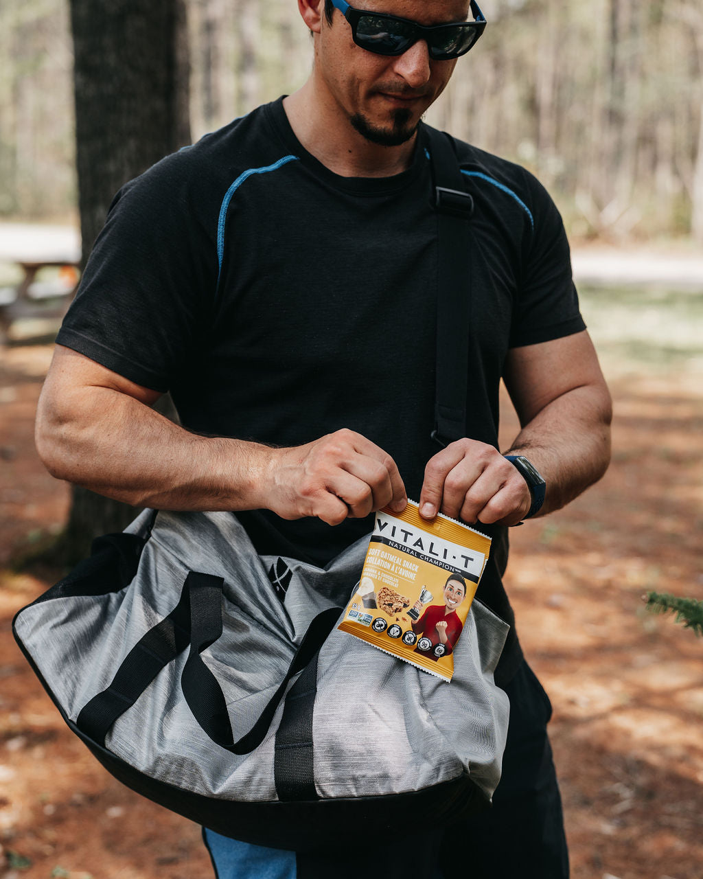 Homme sportif tenant une collation à l'avoine bananes et chocolat Vitali-T dans les mains.